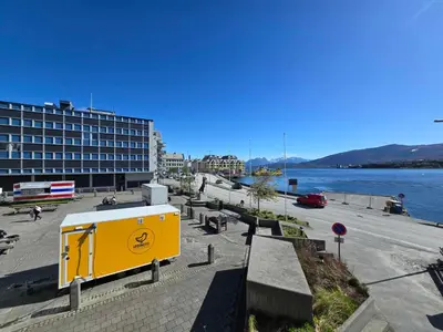 a yellow dumpster on the side of a street next to the water at Oceanview Apartment Aalesund in Ålesund