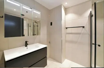 a white bathroom with a sink and a shower at Oceanview Apartment Aalesund in Ålesund
