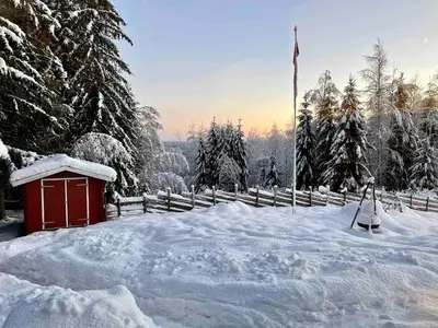 a snow covered yard with a red shed and a flag at Cottage w Wilderness Feeling 20 min from airport in Maura