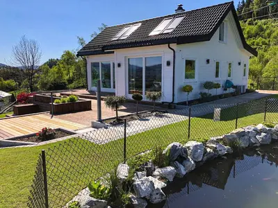 a small white house with a fence next to a pond at Hytte Hammarslandbakken in Bergen