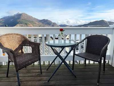 a glass table and two chairs on a balcony at Jibben Hotell in Måløy