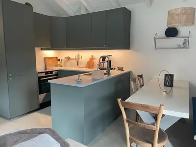 a kitchen with black cabinets and a table and a counter at Beautiful Cottage by the Sea in Tysse