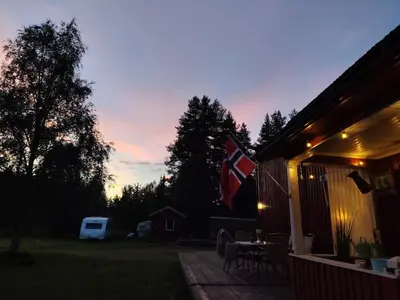 a house with a flag on a deck at sunset at Landgård Feriehus in Trysil