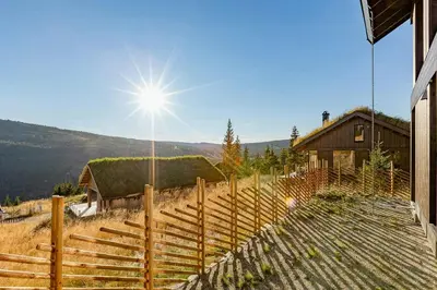 a fence next to a house with the sun in the sky at Modern Cabin With Ski In Out At Kvitfjell in Favang
