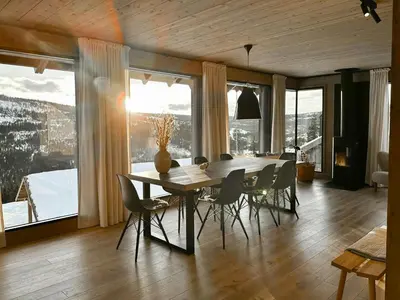 a dining room with a table and chairs and windows at Modern Cabin With Ski In Out At Kvitfjell in Favang