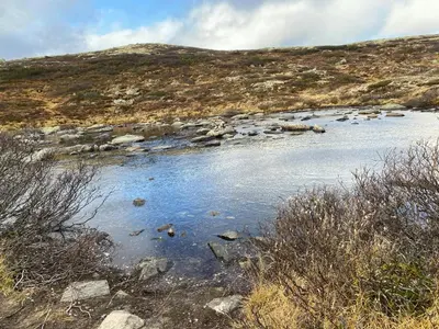 a river on a hill with rocks in the water at Traditional Cabin In Nøsterbølia in Uvdal