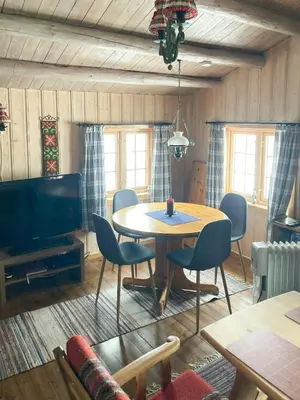 a living room with a table and chairs and a television at Traditional Cabin In Nøsterbølia in Uvdal