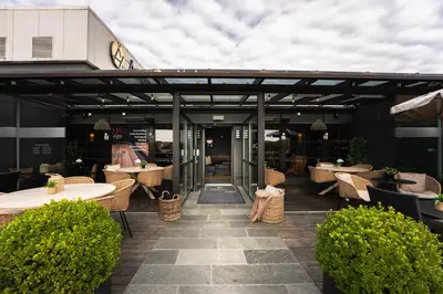 a patio with tables and chairs and a building at Ågotnes Hotell in Ågotnes