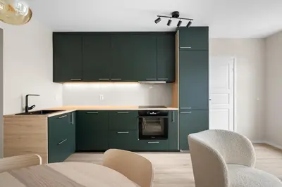 a kitchen with green cabinets and a table and chairs at Bergen Beds Apartments I Urban Escape in Bergen