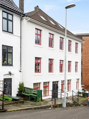 a white building with red windows and a green bench at Bergen Beds Apartments I Urban Escape in Bergen