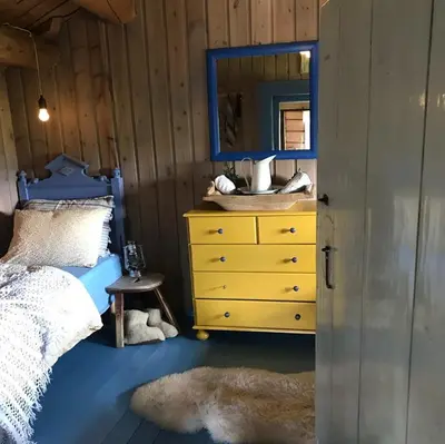 a bedroom with a yellow dresser and a mirror at Charming lodge from 1888 in Sel