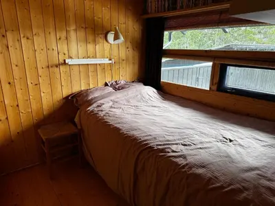 a bed in a wooden room with a window at Ål-hytte i Snertingdal på solrik tomt med suveren beliggenhet in Gjøvik