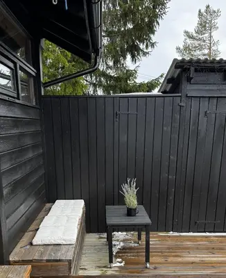 a patio with a table and a black fence at Ål-hytte i Snertingdal på solrik tomt med suveren beliggenhet in Gjøvik