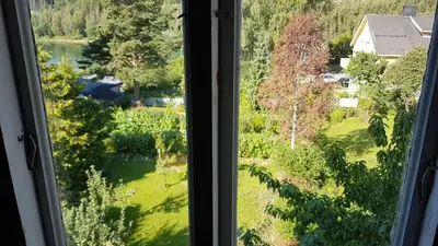 a window with a view of a field and a river at Large Family Friendly Apartment in Lillehammer