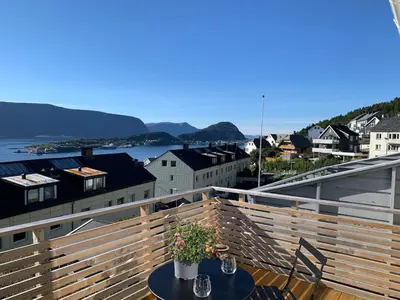 a table on a balcony with a view of a city at Elegant Townhouse, Breathtaking Views and Free Parking in Ålesund