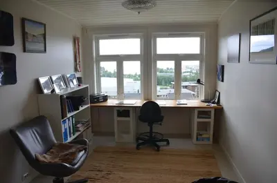 an office with a desk and a chair and two windows at House with all amenities for rent in Steinkjer
