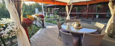 a wooden deck with a table and chairs and flowers at Cabin Room on DaVita Ranch in Tranhaug