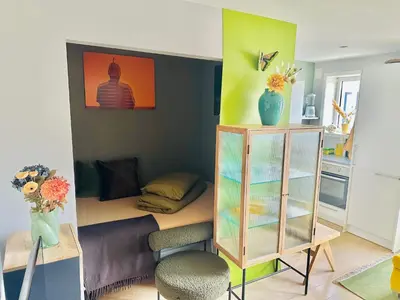 a living room with a couch and a shelf with flowers at Stylish free parking Studio central with balcony in Ålesund
