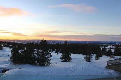 a snow covered hill with trees and the sunset at Hafjelltoppen-New apartment with a beautiful view and high standard in Hafjell