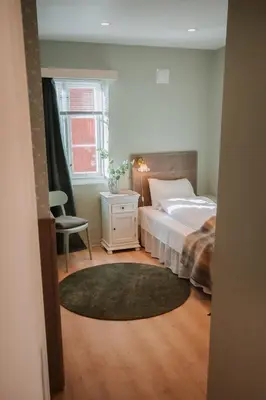 a bedroom with a bed and a chair and a window at Helgaker Gård in Gran