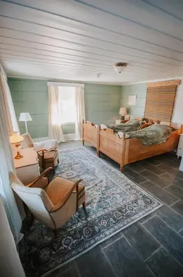 a bedroom with two beds and a chair and a couch at Helgaker Gård in Gran