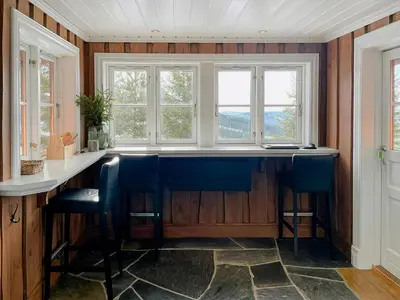 a kitchen with a bar with blue chairs and windows at Modern Cabin With Ski In-Out In Hafjell in Øyer