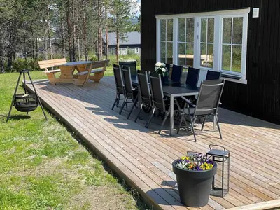 a wooden deck with a table and chairs on it at Ny, stor hytte nær Røros sentrum! in Røros