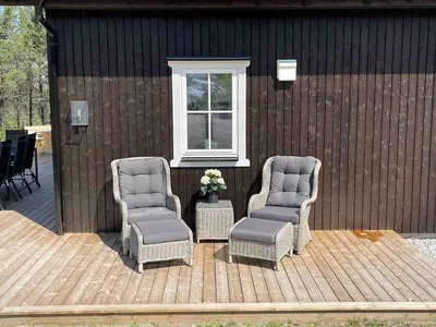 two chairs sitting on a wooden deck next to a window at Ny, stor hytte nær Røros sentrum! in Røros