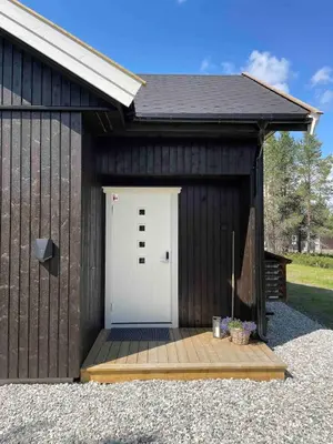 a garage with a white door and a wooden deck at Ny, stor hytte nær Røros sentrum! in Røros