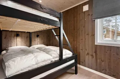 a bedroom with a bunk bed in a wooden wall at Ny, stor hytte nær Røros sentrum! in Røros
