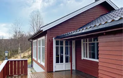 a red house with a white door on a deck at 3 Bedroom Amazing Home In Haddal in Haddal