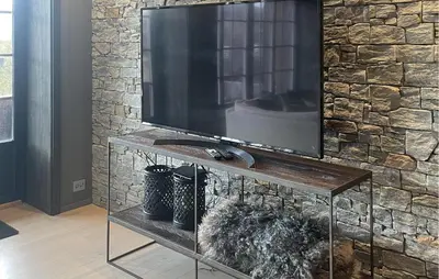 a television on a stand in a room with a stone wall at Stunning Apartment In Hovden I Setesdal in Hovden