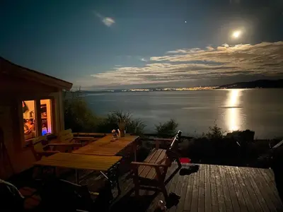 a deck with a view of a lake at night at En perle i Trondheimsfjorden in Trondheim