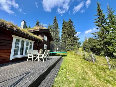 a wooden deck with a table and chairs on a house at Traditional mountain cabin in Valdres in Blomstølen