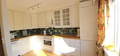 a white kitchen with white cabinets and a window at Midt i byn in Bergen