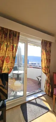 a room with a sliding glass door with a view of the ocean at Midt i byn in Bergen