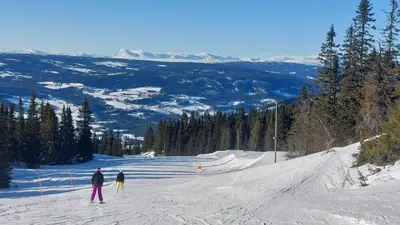 a group of people skiing down a snow covered slope at Tømmerhytte i Valdres med panoramautsikt over fjellene in Aurdal