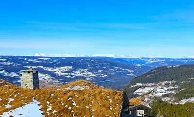 a building on top of a hill with snow at Tømmerhytte i Valdres med panoramautsikt over fjellene in Aurdal