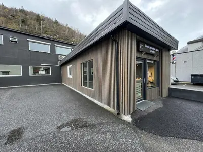 a brown building with a parking lot next to a building at Sentral fantastisk leilighet in Øvre Årdal