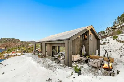 a small house in the snow with a view of a river at Cabin Overlooking Ryfylke Fjord in Høyvik