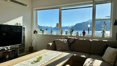 a living room with a couch and a large window at Live right by the Sognefjord in Sogndal