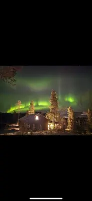 an aurora in the sky over a building and trees at Veltelia Resort in Nes i Ådal