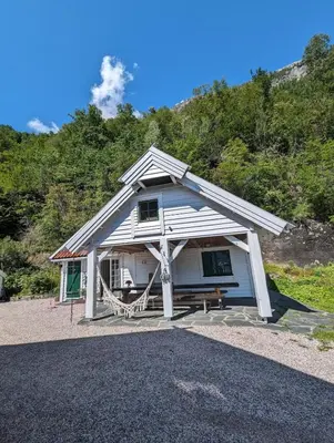 a small white house with a porch and a bench at Charming guest house with amazing view in Kvam