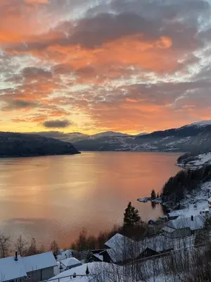 a sunset over a lake with snow on the ground at Faleide View in Stryn