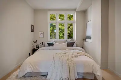 a white bedroom with a large bed with a window at Stay Panorama - Best view in Bergen l 1-Bedroom in Bergen