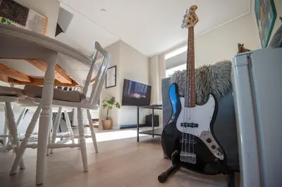 a guitar in a living room with a table and chairs at 200 meters to Bryggen in charming Sandviken in Bergen