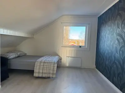 a small bedroom with a bed and a window at Beautiful spacious home w garden in Trondheim