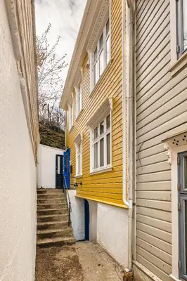 a yellow building with stairs next to a house at Stay Panorama - Best view in Bergen l 2-Bedroom in Bergen