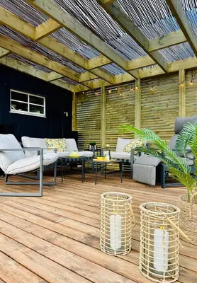 a patio with couches and tables on a wooden floor at Scenic Private House Surrounded by Nature in Sæbø
