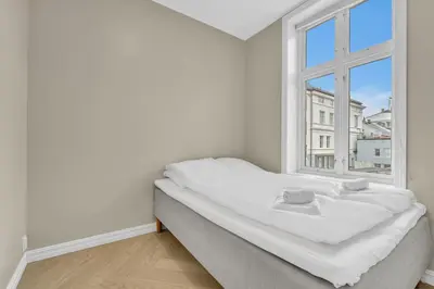 a white bedroom with a bed and a window at Urban Elegant Apartment in Bergen